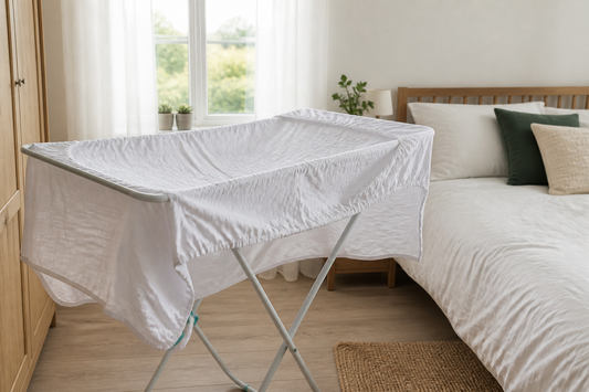 Clean mattress protector air-drying on a rack beside a neatly made bed